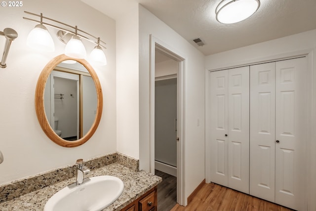 bathroom featuring vanity, wood-type flooring, and a textured ceiling