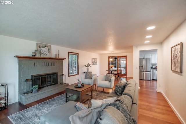 living room featuring a brick fireplace and hardwood / wood-style flooring