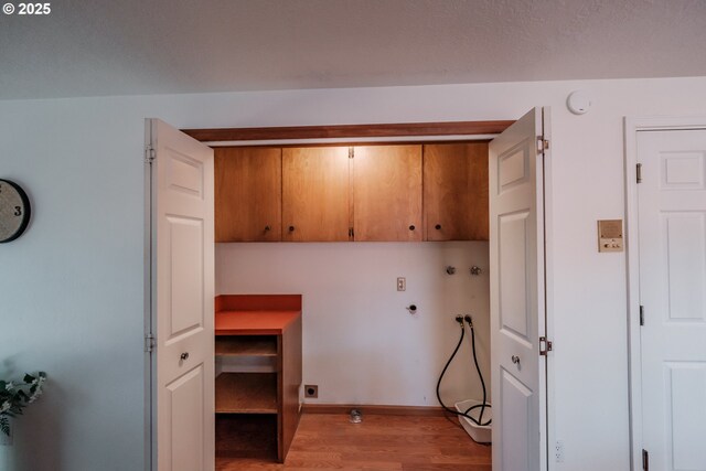 clothes washing area featuring cabinets, hookup for a washing machine, and light hardwood / wood-style floors