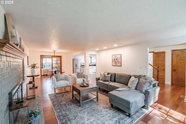 living room featuring hardwood / wood-style floors, a textured ceiling, and a fireplace