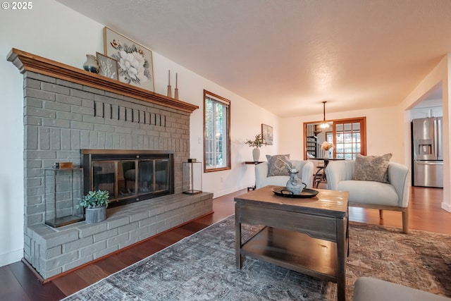 living room with dark hardwood / wood-style flooring and a brick fireplace