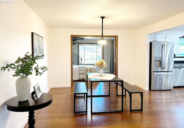 dining room featuring dark wood-type flooring and a textured ceiling