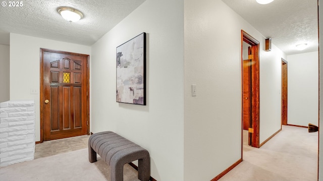 hall with a textured ceiling and light carpet