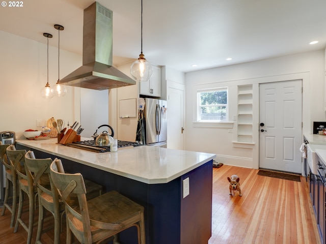 kitchen with white cabinetry, hanging light fixtures, island exhaust hood, kitchen peninsula, and appliances with stainless steel finishes