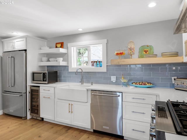 kitchen featuring appliances with stainless steel finishes, light hardwood / wood-style floors, white cabinetry, and sink