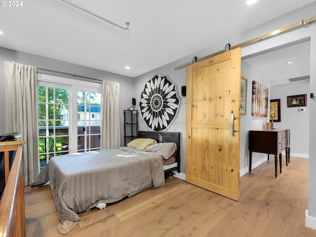 bedroom featuring a barn door and light hardwood / wood-style flooring