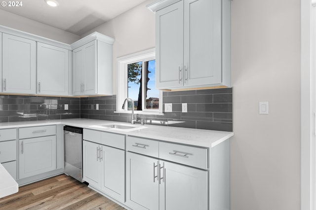 kitchen with sink, backsplash, white cabinetry, dishwasher, and light hardwood / wood-style floors