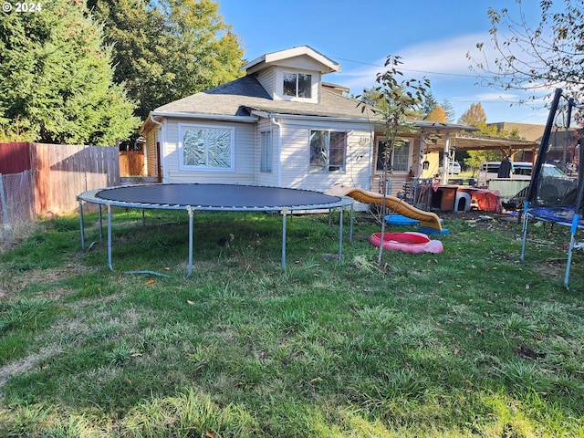 back of house with a playground, a yard, and a trampoline