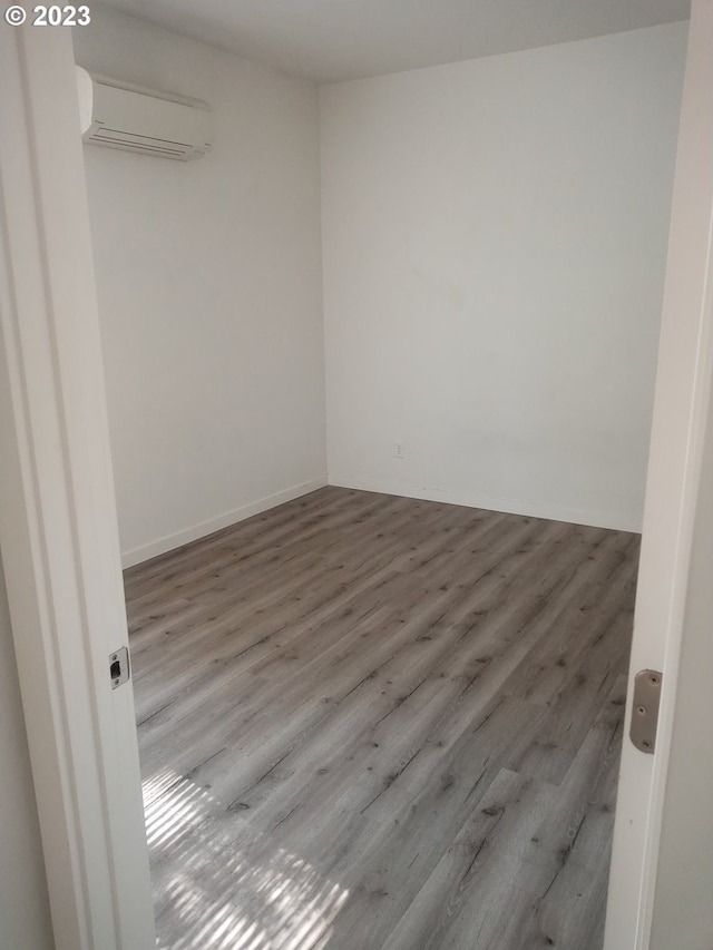 empty room featuring an AC wall unit and light hardwood / wood-style flooring