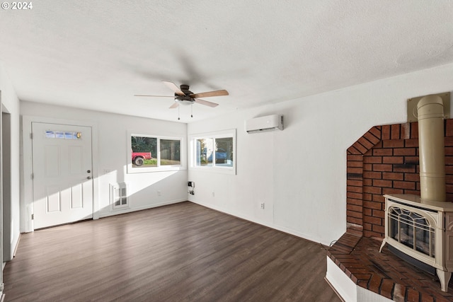 unfurnished living room featuring an AC wall unit, a wood stove, dark wood-type flooring, and a textured ceiling