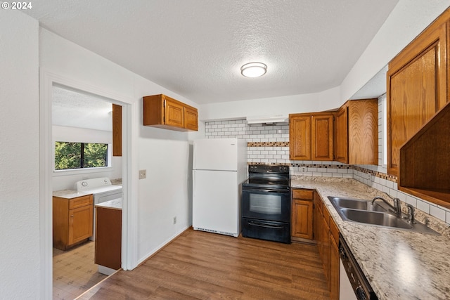 kitchen featuring a textured ceiling, white refrigerator, black range with electric stovetop, and sink