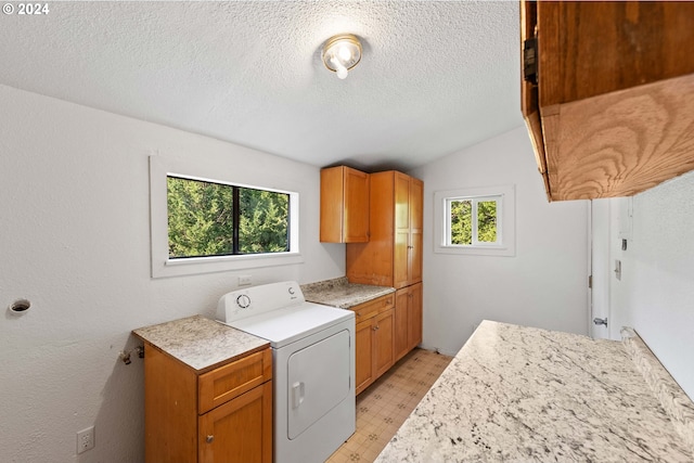 laundry room featuring cabinets, washer / dryer, a textured ceiling, and a healthy amount of sunlight