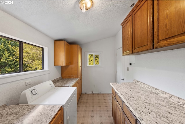 laundry room with cabinets, a textured ceiling, and washing machine and dryer