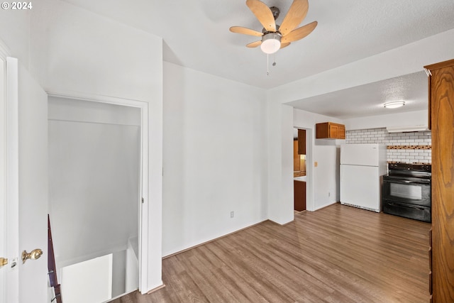 kitchen with light wood-type flooring, a textured ceiling, ceiling fan, white refrigerator, and black electric range