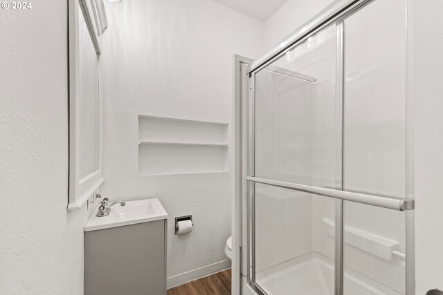 bathroom featuring hardwood / wood-style flooring, vanity, toilet, and walk in shower