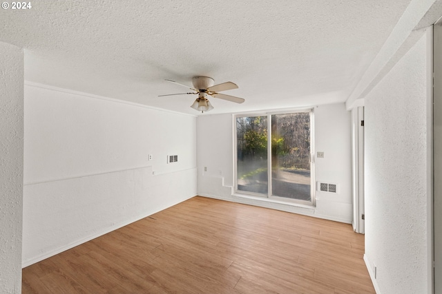 spare room featuring ceiling fan, light wood-type flooring, and a textured ceiling