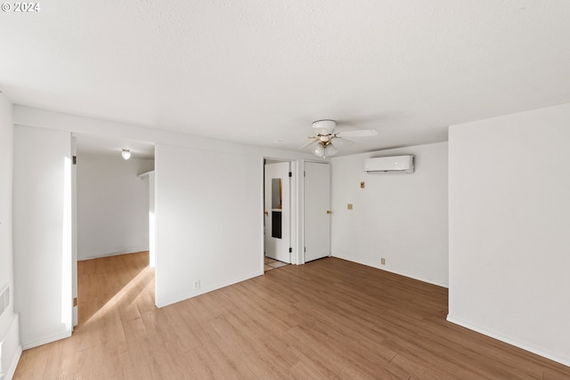 empty room featuring wood-type flooring, an AC wall unit, and ceiling fan