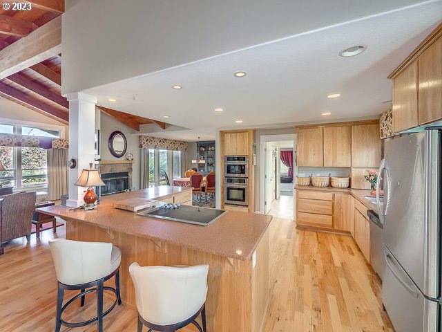 kitchen with light brown cabinets, a kitchen bar, light wood-type flooring, kitchen peninsula, and appliances with stainless steel finishes