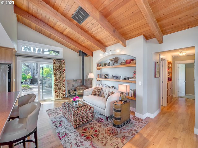 living room with built in shelves, wooden ceiling, and a wood stove