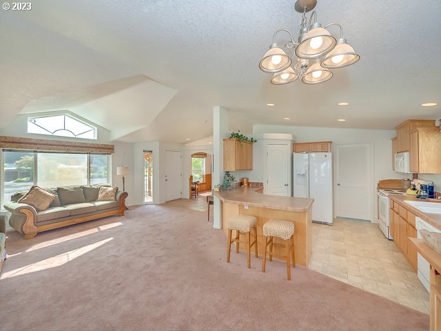 kitchen featuring white appliances, a kitchen breakfast bar, light colored carpet, kitchen peninsula, and an inviting chandelier