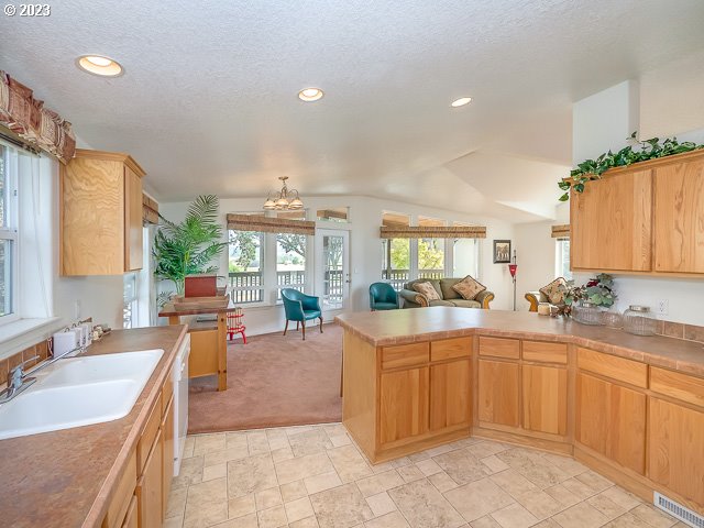 kitchen featuring sink, a textured ceiling, lofted ceiling, light carpet, and kitchen peninsula