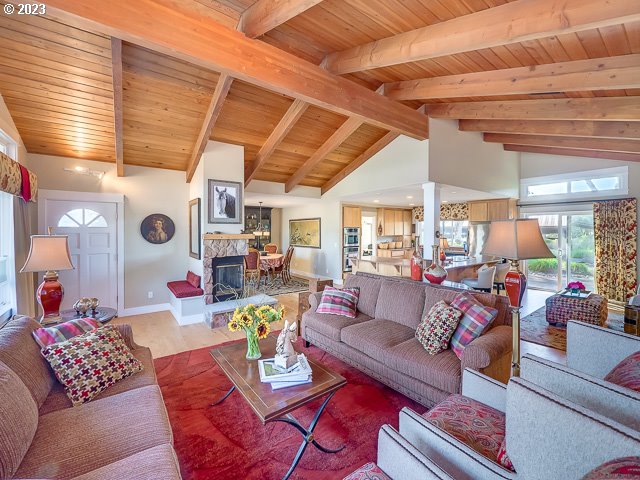 living room featuring beam ceiling, wood ceiling, a stone fireplace, and high vaulted ceiling