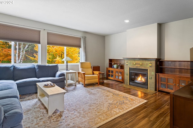 living room with a textured ceiling, a tile fireplace, and dark hardwood / wood-style floors