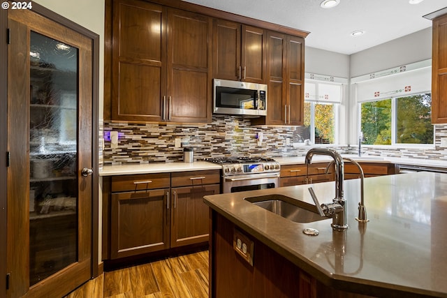 kitchen with hardwood / wood-style flooring, decorative backsplash, sink, and stainless steel appliances