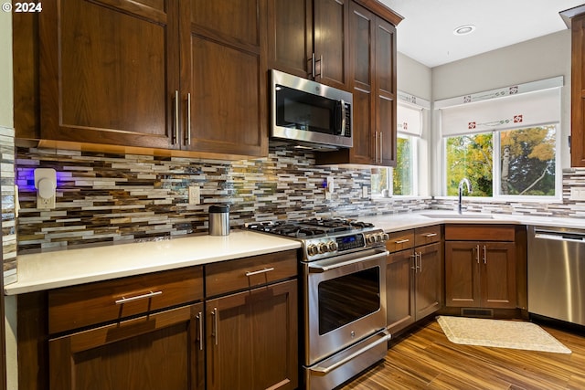 kitchen with tasteful backsplash, hardwood / wood-style floors, stainless steel appliances, and sink