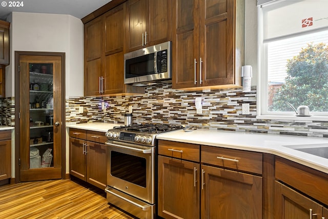 kitchen with backsplash, light hardwood / wood-style floors, and stainless steel appliances