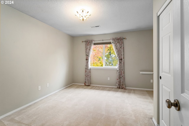 spare room featuring light carpet and a textured ceiling