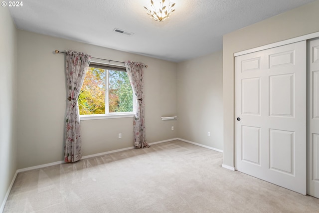 empty room with light colored carpet and a textured ceiling