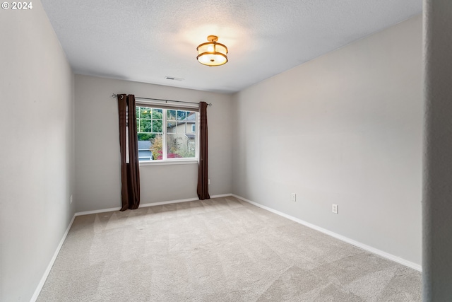 carpeted empty room featuring a textured ceiling