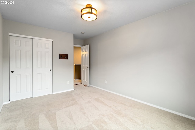 unfurnished bedroom featuring light carpet and a closet