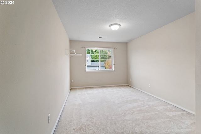 unfurnished room with light colored carpet and a textured ceiling