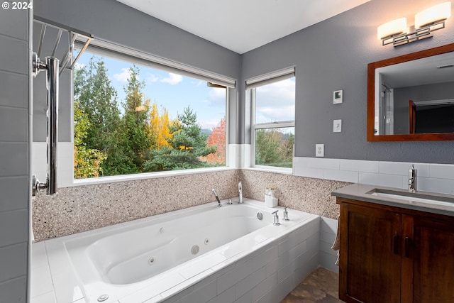 bathroom with tiled tub, plenty of natural light, and vanity