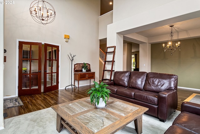 living room with hardwood / wood-style floors, a towering ceiling, french doors, and an inviting chandelier