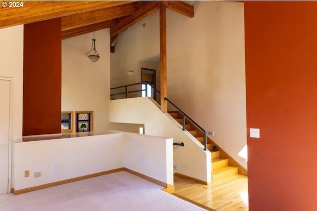 stairway with high vaulted ceiling, beam ceiling, and hardwood / wood-style floors