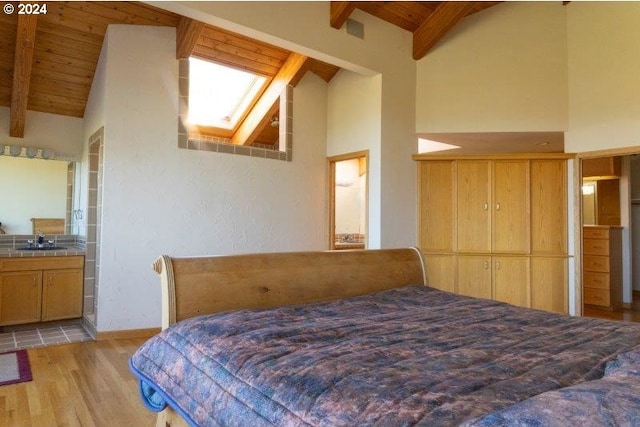 bedroom with wooden ceiling, beamed ceiling, ensuite bathroom, and a skylight