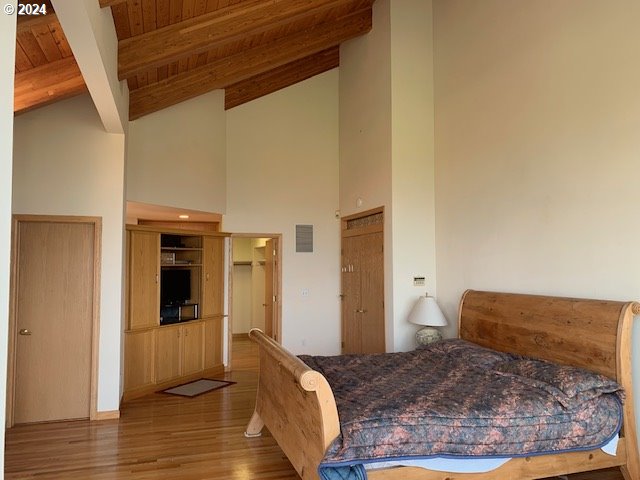 bedroom with wood ceiling, light wood-type flooring, high vaulted ceiling, and beamed ceiling