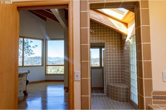 bathroom featuring wood-type flooring, a mountain view, and lofted ceiling with skylight