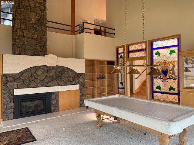 game room with a high ceiling, pool table, a fireplace, and plenty of natural light