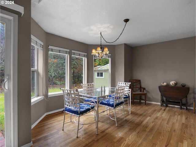 dining space featuring wood-type flooring, a textured ceiling, and an inviting chandelier