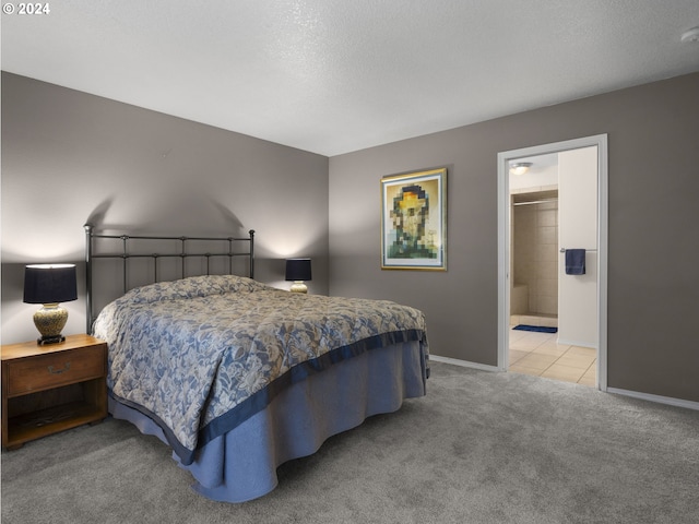 bedroom with ensuite bathroom, a walk in closet, and light carpet