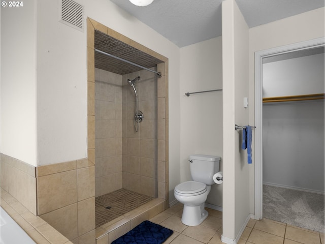 bathroom with tiled shower, tile patterned flooring, and toilet