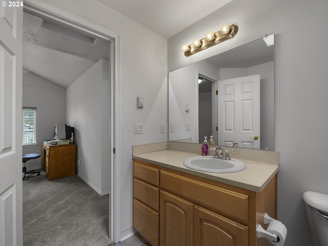 bathroom with lofted ceiling, vanity, a textured ceiling, and toilet