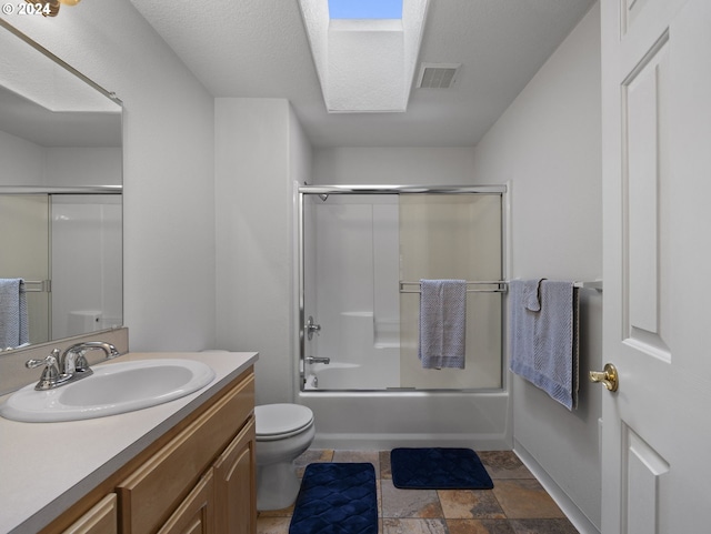 full bathroom featuring vanity, a skylight, toilet, and enclosed tub / shower combo