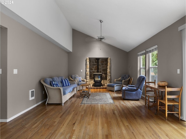 living room featuring hardwood / wood-style floors, a wood stove, ceiling fan, and lofted ceiling