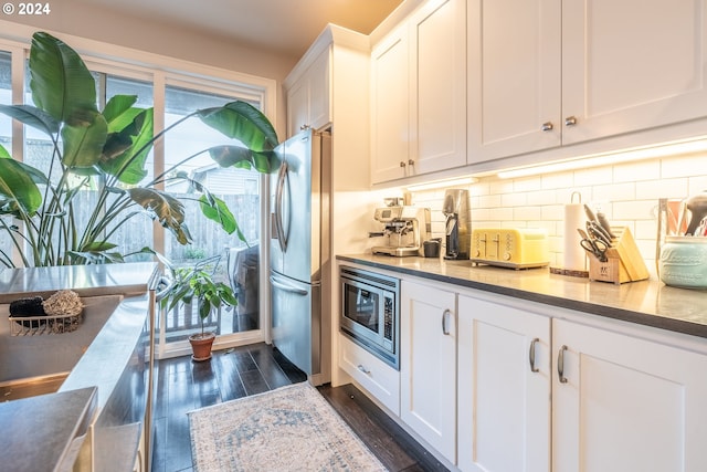 kitchen with tasteful backsplash, dark hardwood / wood-style floors, stainless steel appliances, and white cabinets