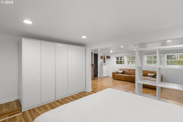 bedroom with multiple windows, light hardwood / wood-style floors, and a closet